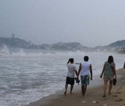 Un grupo de personas camina sobre una playa de Acapulco, horas antes de la llegada del huracán 'Otis'. Foto: REUTERS