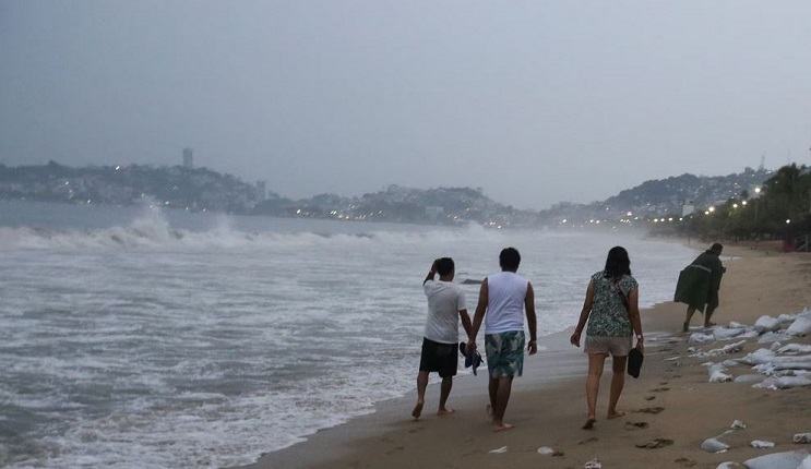 Un grupo de personas camina sobre una playa de Acapulco, horas antes de la llegada del huracán 'Otis'. Foto: REUTERS