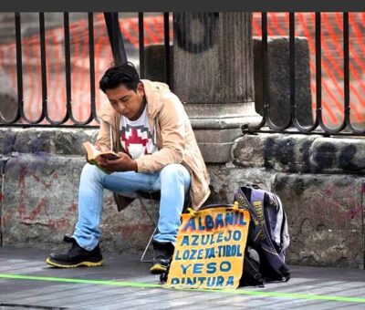 Un hombre lee mientras ofrece servicios de albañilería, frente a la Catedral Metropolitana en Ciudad de México, en agosto de 2020. MARCO UGARTE (AP)